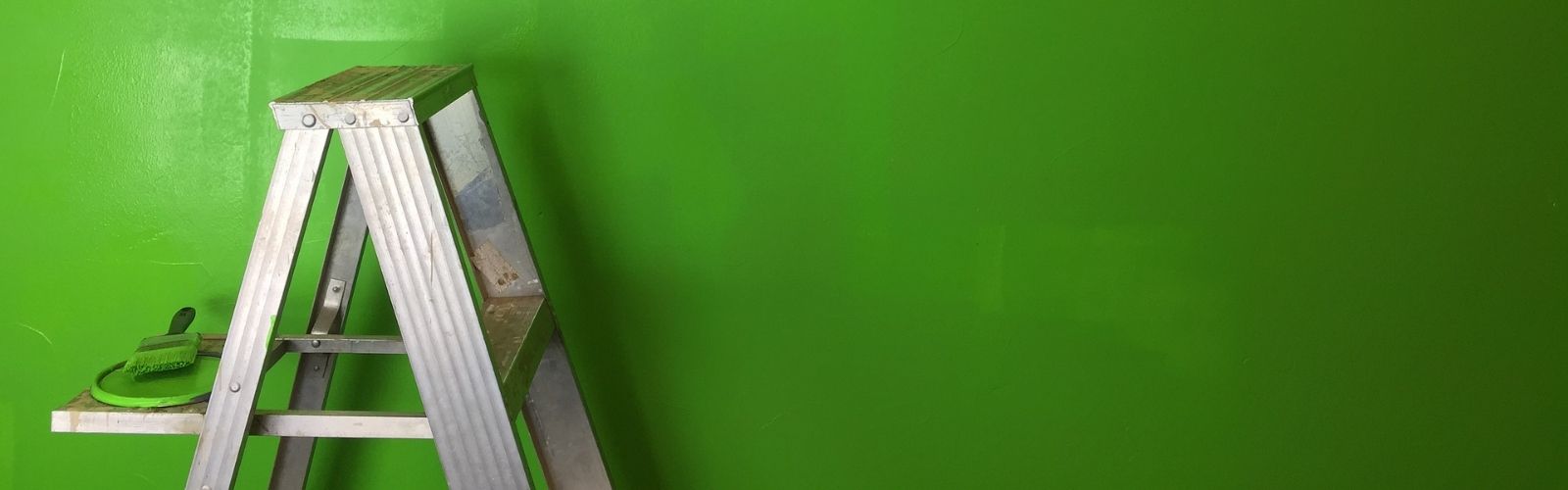 a ladder in front of a green wall